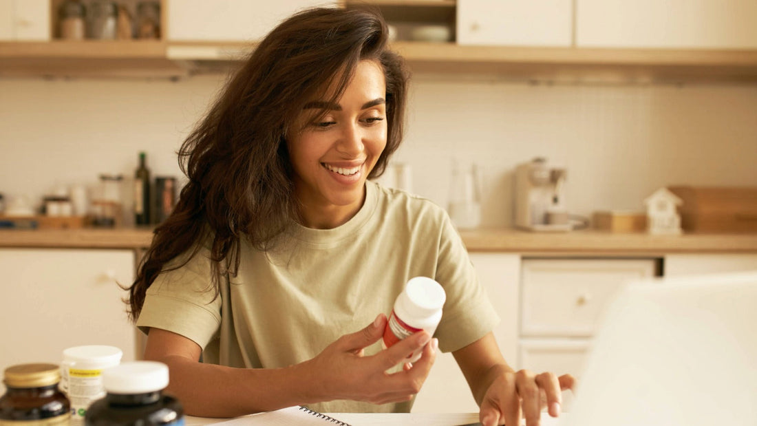 Woman reviewing a dietary supplement bottle at home, representing essential nutrients for bone, heart and immune health.