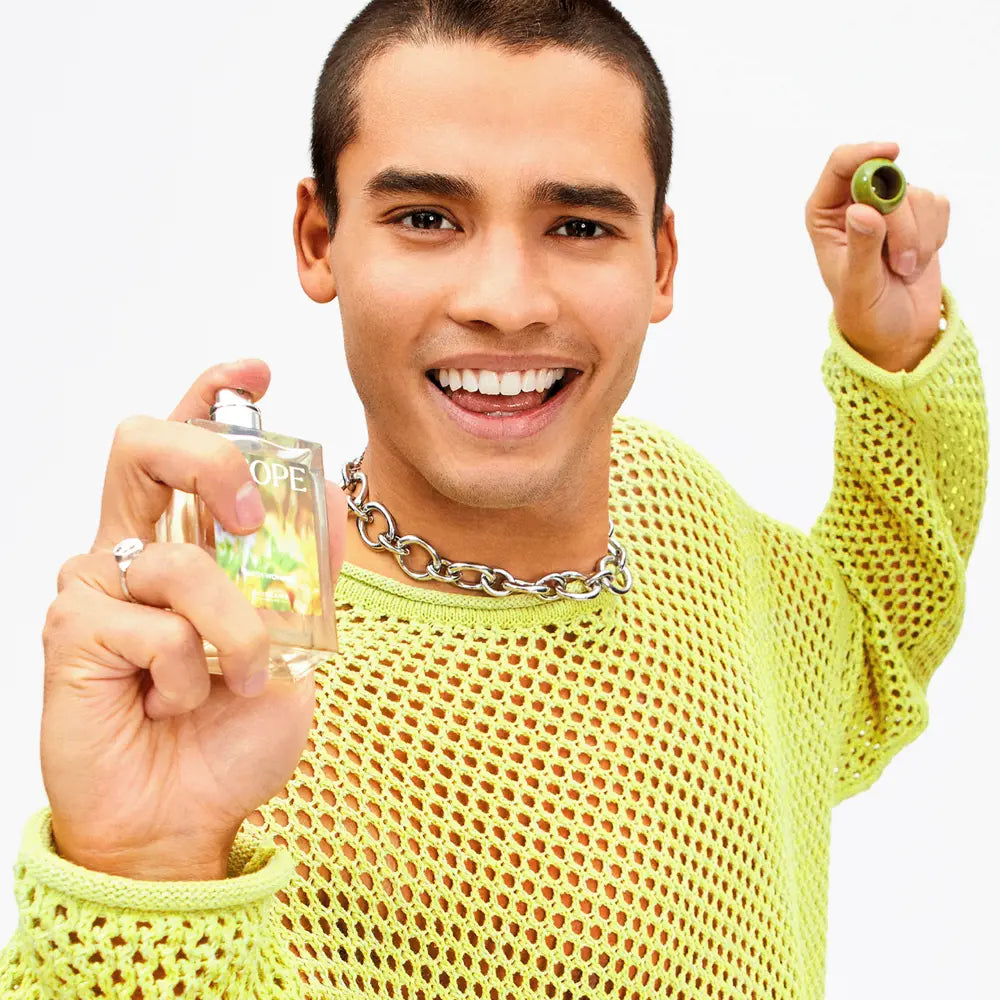 Man in a yellow sweater holding a glass with a green olive and a shot glass.