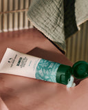 The Body Shop Seaweed cleansing mask being applied to skin with a green towel in the background.