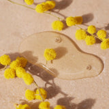 Yellow flowers on a beige surface with a clear droplet.